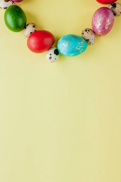 Vista superior ovos pintados Moldura de Páscoa em forma de círculo em um fundo amarelo. Espaço de cópia — Fotografia de Stock