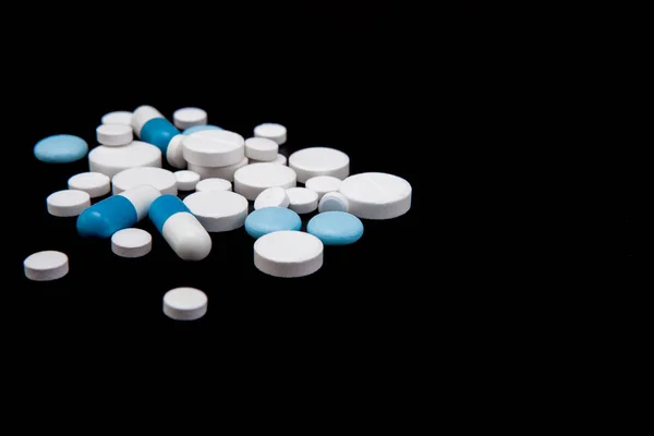 Comprimidos e cápsulas sobre um fundo preto. Medicamentos e suplementos dietéticos — Fotografia de Stock