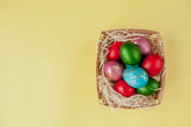 Mutlu Paskalya yumurtaları sarı arka plan. Kutlama kartı, promosyon ve poster için sepetteki altın parlayan yumurtalar. Boşluğu kopyala.