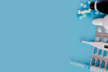 Soğuk algınlığı ve grip tedavisinde. Çeşitli ilaçlar, bir termometre, spreyler tıkalı burun ve boğaz üzerinde mavi bir arka plan baş belası. Uzay kopyalayın. Tıp düz yatıyordu.