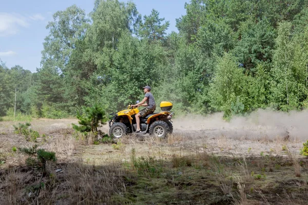 Az ember lovaglás egy sárga quad ATV minden terepjáróval a homokos erdőben. Extrém sport mozgás, kaland, turistalátványosság. — Stock Fotó