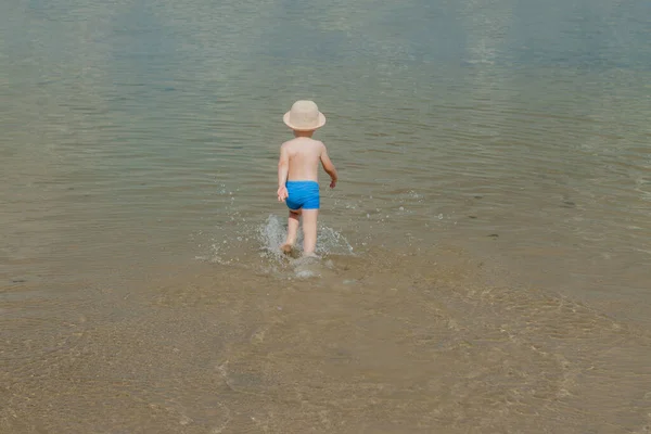 Słodkie dziecko działa od morza fale na plaży — Zdjęcie stockowe