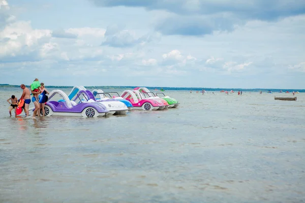 Svityaz- wrzesień 2019: kolorowe stare zabytkowe plastikowe katamarany i łodzie w pobliżu drewnianego molo na brzegu dużego jeziora — Zdjęcie stockowe