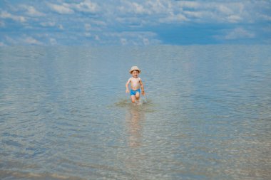 Sahilde deniz dalgaları çalışan şirin çocuk.