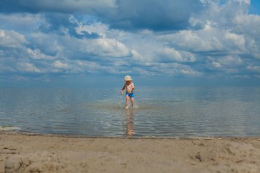 Sahilde deniz dalgaları çalışan şirin çocuk.