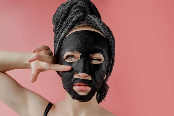 Jonge Vrouw Toe Passen Zwarte Cosmetische Stof Gezichtsmasker Roze Achtergrond — Stockfoto