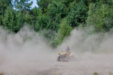 Kyiv - Eylül 2019 Adam kumlu bir ormanda sarı bir ATV ile arazi aracına biniyor. Ekstrem spor hareketleri, macera, turistik eğlence