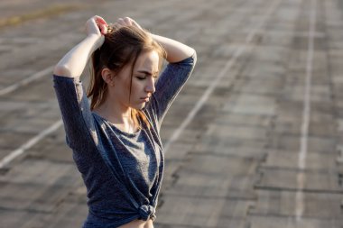 Genç bayan yazın stadyumda antrenman yapıyor. Sporcu kadın, dışarıda egzersiz yapmadan önce ısınıyor. Sağlıklı yaşam tarzı.