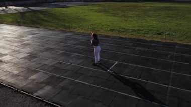 Bayan sporcu bacaklarını kardiyo antrenmanına hazırlıyor. Fitness koşucusu ısınma egzersizi yapıyor. Kadın koşucu dışarıda ısınıyor. Sporcu bir stadyumdaki koşu pistinde ısınıyor ve ısınıyor.