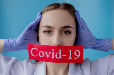 Doktor kadın mavi arka planda kurtarılmış Coronavirüs olan kırmızı kağıda işaret ediyor. Dünya Sağlık Örgütü WHO, COVID-19 adlı Coronavirus hastalığına yeni bir resmi isim verdi.