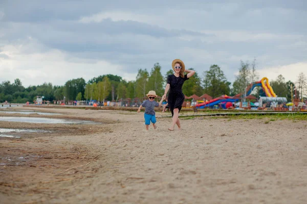 一个年轻漂亮的姑娘和她的儿子在沙滩上奔跑 — 图库照片