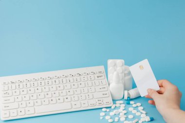 İlaç ve klavyeli alışveriş arabası oyuncağı. Haplar, su toplayan paketler, tıbbi şişeler, termometre, mavi arka planda koruyucu maske. - Evet. Sağlık ve internet alışverişi. Metniniz için en üstteki görünüm.