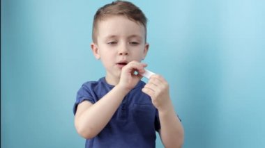 Termometresi olan hasta bir çocuk ateşinin yüksekliğini ölçüyor ve kameraya bakıyor.