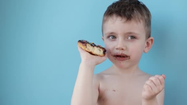 Malý Chlapec Koblihovou Čokoládu Modrém Pozadí Roztomilý Šťastný Chlapec Rozmazaný — Stock video