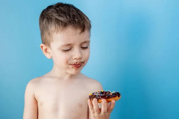 Маленький Мальчик Ест Шоколадный Пончик Синем Фоне Милый Счастливый Мальчик — стоковое фото