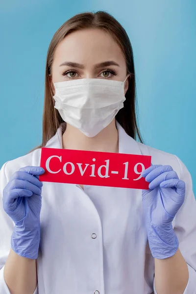 Dokter vrouw met chirurgisch masker wijzend naar rood papier met mesaage Coronavirus op blauwe achtergrond. Wereldgezondheidsorganisatie WHO introduceerde nieuwe officiële naam voor Coronavirus genaamd COVID-19 — Stockfoto