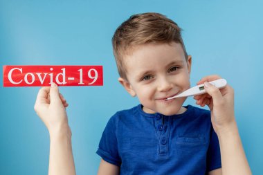 Küçük çocuk mavi arka planda kurtarılmış Coronavirüs olan kırmızı kağıda işaret ediyor. Dünya Sağlık Örgütü WHO, COVID-19 adlı Coronavirus hastalığına yeni bir resmi isim verdi.