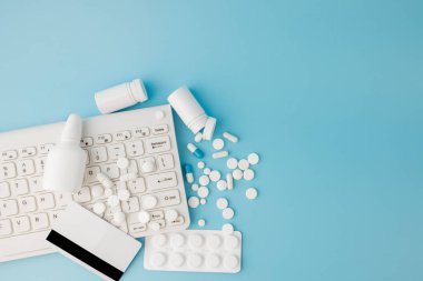 İlaç ve klavyeli alışveriş arabası oyuncağı. Haplar, su toplayan paketler, tıbbi şişeler, termometre, mavi arka planda koruyucu maske. - Evet. Sağlık ve internet alışverişi. Metniniz için en üstteki görünüm.