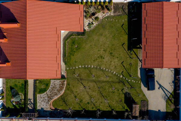 Aerial top view of a private house with paved yard with green grass lawn with concrete foundation floor.