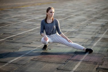 Genç bayan yazın stadyumda antrenman yapıyor. Sporcu kadın, dışarıda egzersiz yapmadan önce ısınıyor. Sağlıklı yaşam tarzı.