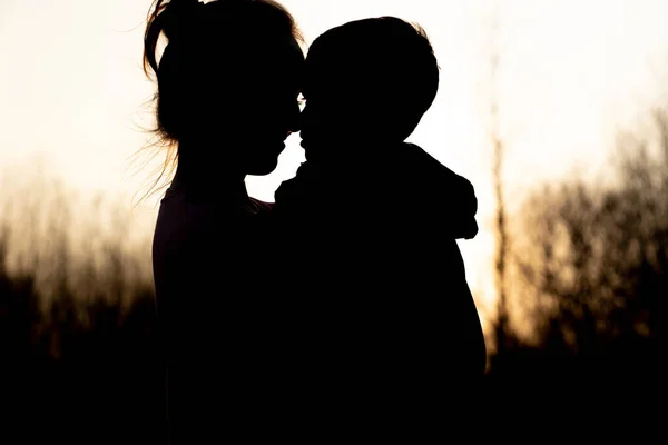 Silhouette of a mother and son playing outdoors at sunset. Mother\'s day concept.