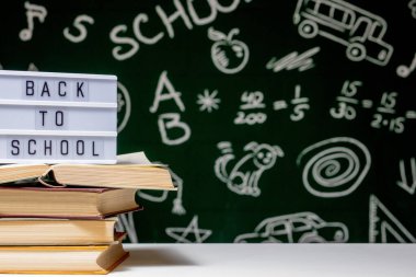 Kitap, kalem ve küre ile okul arka planına yeşil karatahta arka planında beyaz masa üzerinde