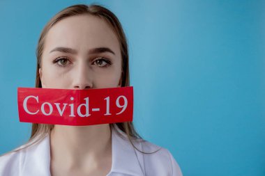 Doktor kadın mavi arka planda kurtarılmış Coronavirüs olan kırmızı kağıda işaret ediyor. Dünya Sağlık Örgütü WHO, COVID-19 adlı Coronavirus hastalığına yeni bir resmi isim verdi.