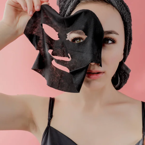 Jonge Vrouw Toe Passen Zwarte Cosmetische Stof Gezichtsmasker Roze Achtergrond — Stockfoto