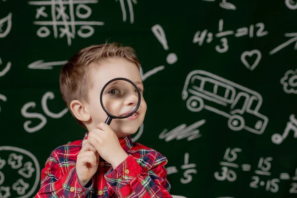 Leuke Slimme Jongen Zit Achter Een Bureau Met Vergrootglas Hand — Stockfoto