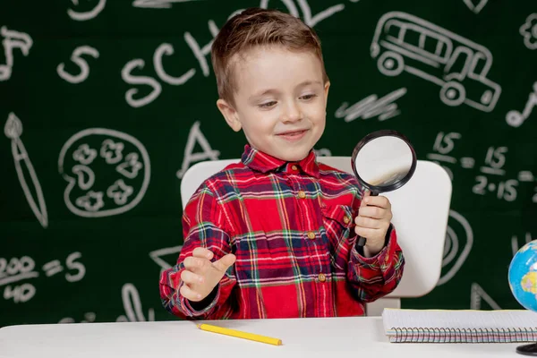 Leuke Slimme Jongen Zit Achter Een Bureau Met Vergrootglas Hand — Stockfoto