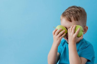 Little Boy mavi arka plan, diyet ve iyi bir sağlık konsepti için egzersiz elinde bir Elma holding.