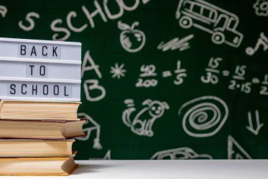 Kitap, kalem ve küre ile okul arka planına yeşil karatahta arka planında beyaz masa üzerinde