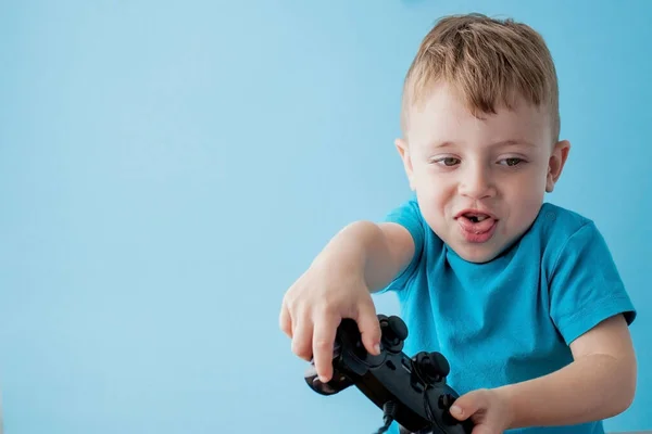 青い服を着た小さな男の子2 3歳は ゲームオンブルーの背景の子供のスタジオの肖像画のための手のジョイスティックを保持します 人々の子供時代のライフスタイルの概念 コピースペースのモックアップ — ストック写真