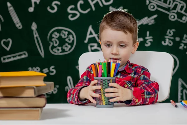 Cute child boy doing homework. Clever kid drawing at desk. Schoolboy. Elementary school student drawing at workplace. Kid enjoy learning. Home schooling. Back to school. Little boy at school lesson.