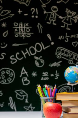 Kitaplar, kalemler ve beyaz masanın üzerindeki elmayla okula geri dön.