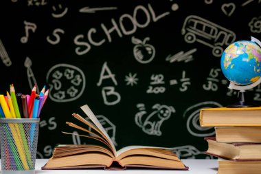 Kitap, kalem ve küre ile okul arka planına yeşil karatahta arka planında beyaz masa üzerinde