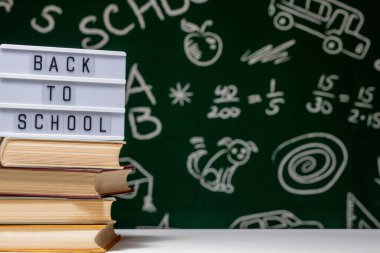 Kitap, kalem ve küre ile okul arka planına yeşil karatahta arka planında beyaz masa üzerinde