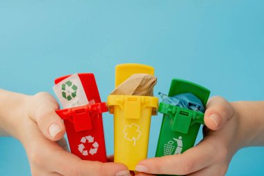 Sarı, yeşil ve kırmızı geri dönüşüm kutularında mavi arka planda geri dönüşüm sembolü var. Şehri düzenli tutar, geri dönüşüm sembolünü bırakır. Doğa koruma kavramı.