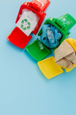 Sarı, yeşil ve kırmızı geri dönüşüm kutularında mavi arka planda geri dönüşüm sembolü var. Şehri düzenli tutar, geri dönüşüm sembolünü bırakır. Doğa koruma kavramı.