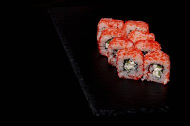 Siyah arka planda somon, peynir ve salatalıklı Philadelphia dürümü. Suşi Philadelphia.