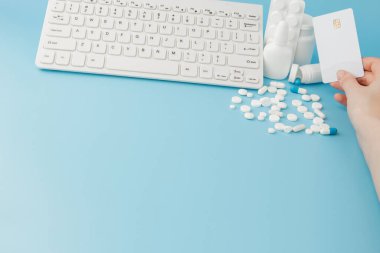 İlaç ve klavyeli alışveriş arabası oyuncağı. Haplar, su toplayan paketler, tıbbi şişeler, termometre, mavi arka planda koruyucu maske. - Evet. Sağlık ve internet alışverişi. Metniniz için en üstteki görünüm.