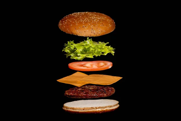 飞行配料汉堡或芝士汉堡在一个孤立在黑暗背景下的木制小切菜板上 汉堡漂浮在桌子上方的空气中 案文的篇幅 — 图库照片