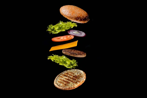 飞行配料汉堡或芝士汉堡在一个孤立在黑暗背景下的木制小切菜板上 汉堡漂浮在桌子上方的空气中 案文的篇幅 — 图库照片