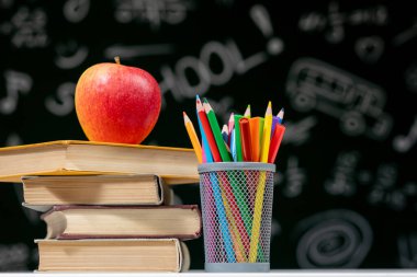 Kitaplar, kalemler ve beyaz masanın üzerindeki elmayla okula geri dön.