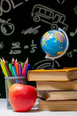 Kitaplar, kalemler ve beyaz masanın üzerindeki elmayla okula geri dön.