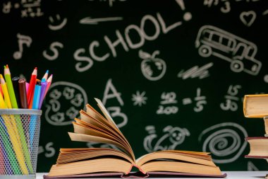 Kitap, kalem ve küre ile okul arka planına yeşil karatahta arka planında beyaz masa üzerinde