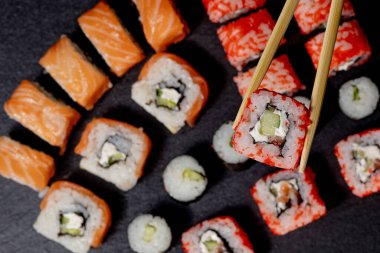 Siyah arkaplanda suşi rulosu. Philadelphia balık, Japon somonu. Lezzetli suşi, pirinç, salatalık, geleneksel wasabi taze, sağlıklı, çiğ gurme..