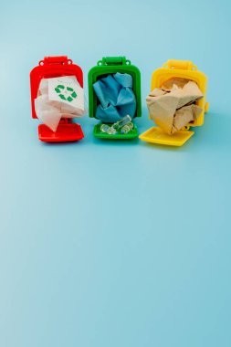 Sarı, yeşil ve kırmızı geri dönüşüm kutularında mavi arka planda geri dönüşüm sembolü var. Şehri düzenli tutar, geri dönüşüm sembolünü bırakır. Doğa koruma kavramı.