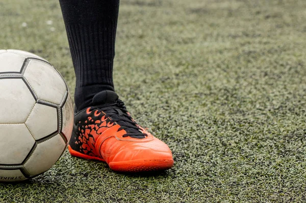 soccer ball with his feet on the football field