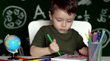 Ev ödevi yapan sevimli çocuk. Masada çizim yapan zeki bir çocuk. Öğrenci çocuk. İlkokul öğrencisi iş yerinde resim çiziyor. Çocuk öğrenmeyi seviyor. Evde eğitim. Okula dönelim. Okuldaki küçük çocuk..